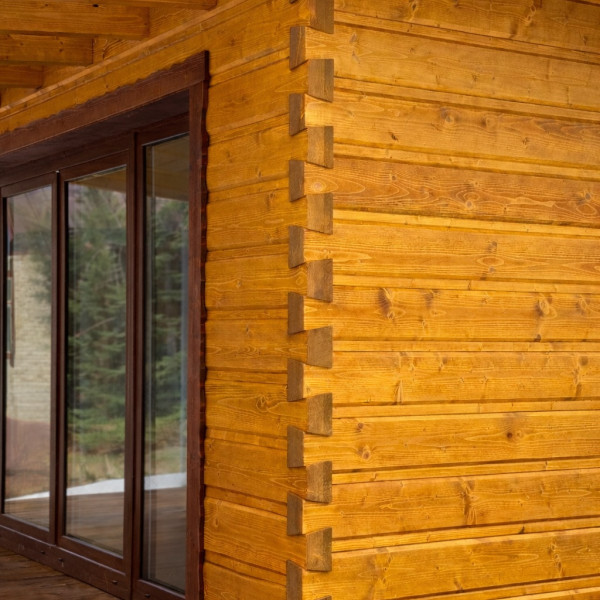 Precízny detail rohu drevenej fasády s obkladom s rybinovým spojom zvýrazňujúcim tradičné stolárske remeslo Domino